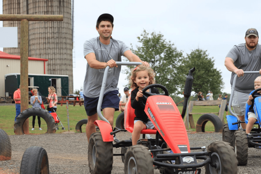 Man pushing child on a pedal car