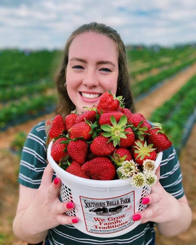 Woman holding an overflowing bucket of Strawberries