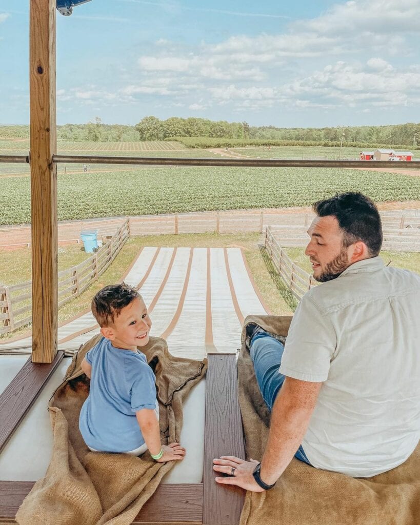 Father and son sitting at the top of giant slide