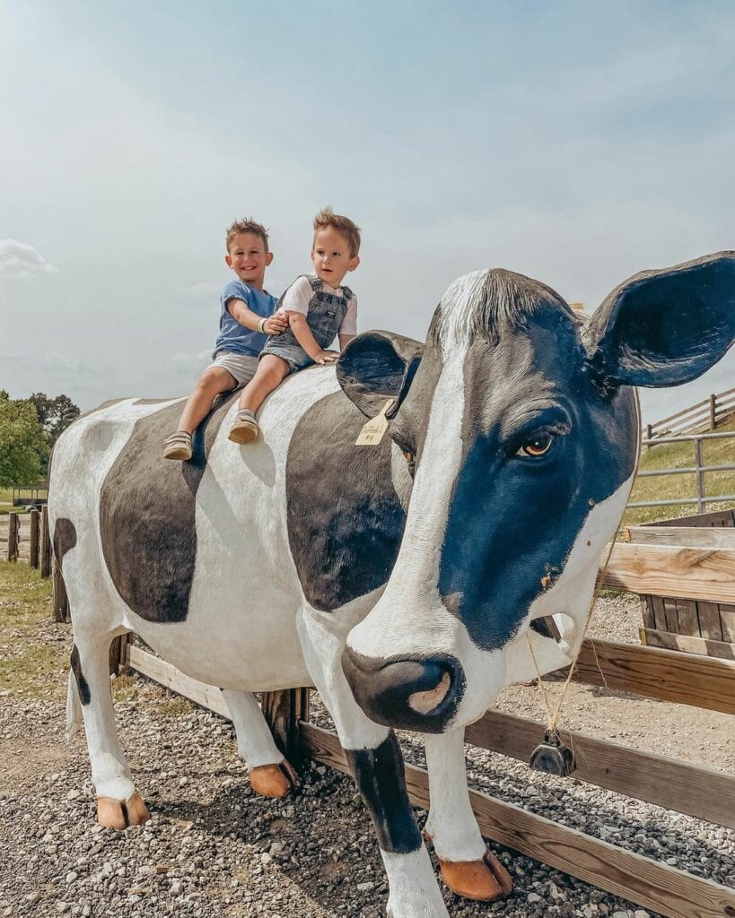 two boys sitting on a cow model