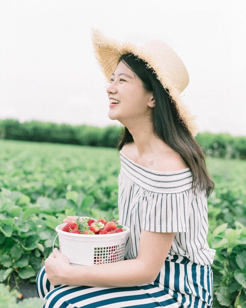 Woman holding a strawberry bucket smiling at farm