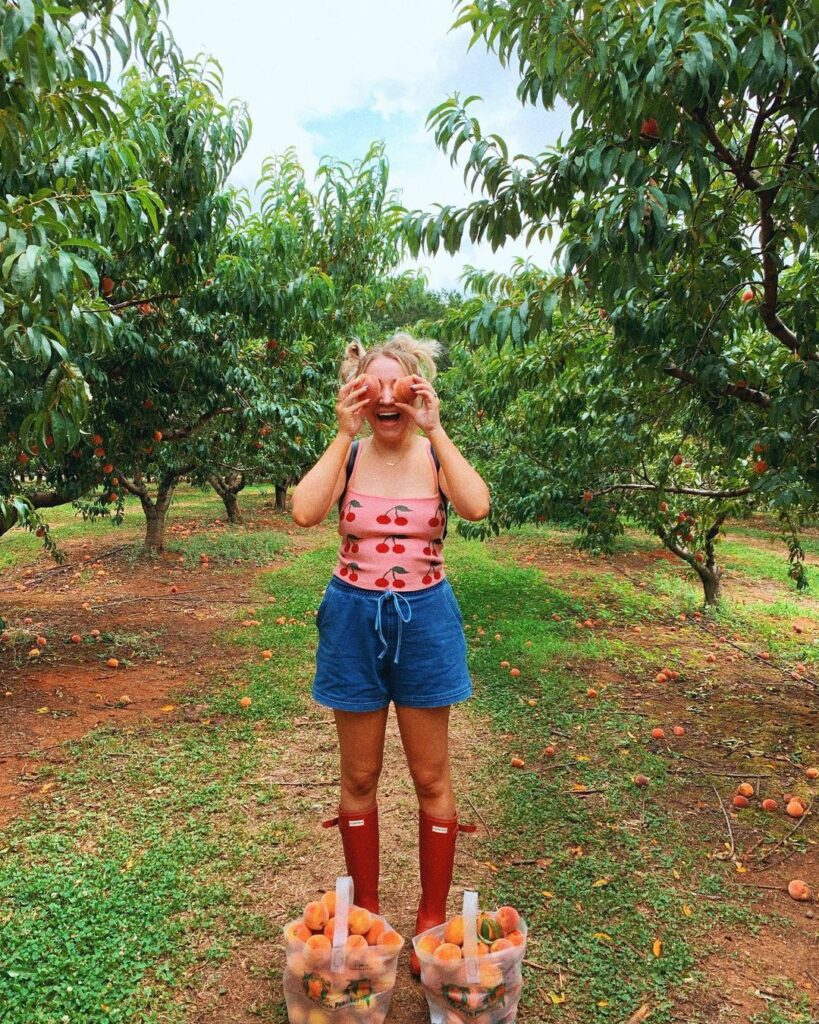 woman holding peaches in front of her eyes at a peach orchard